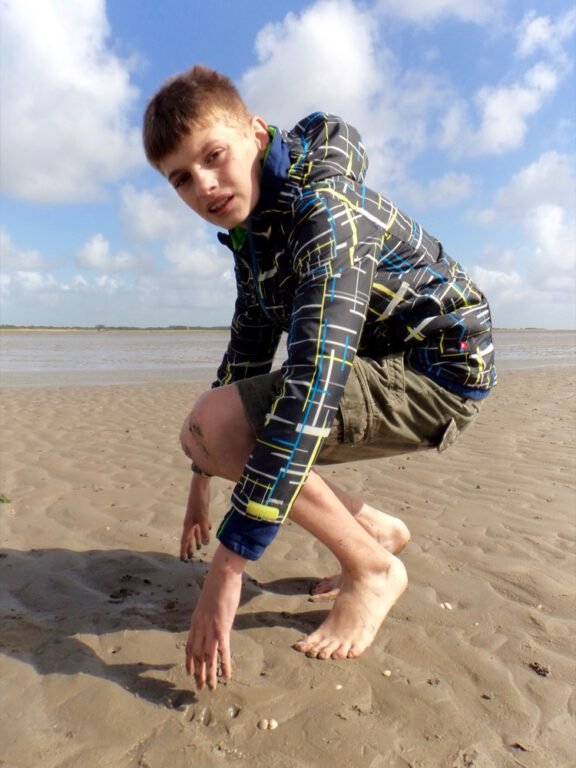 a boy in a jacket on a beach