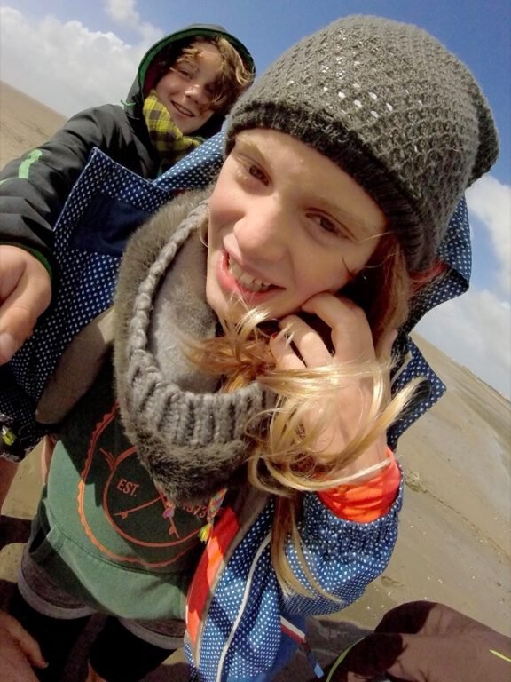 a selfie of two children on a beach