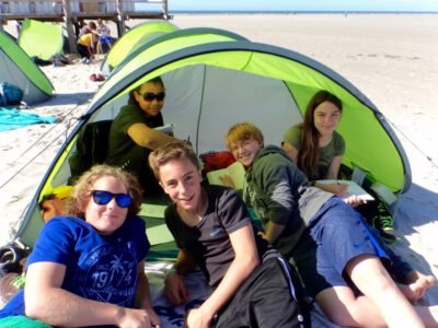 a group of people sitting in a tent on a beach