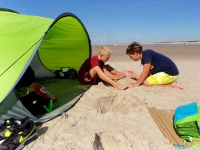 two boys sitting in sand on a beach