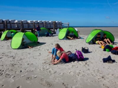 a group of people sitting in a beach with tents