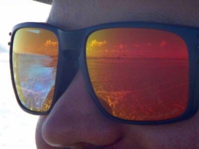 a person wearing sunglasses with a sunset reflection
