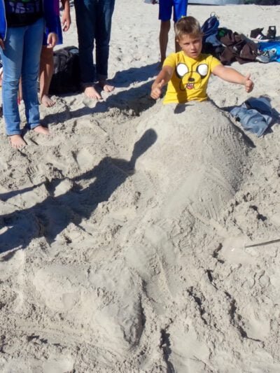 a boy in a yellow shirt on a pile of sand