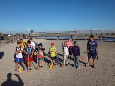 a group of kids holding shovels on a beach
