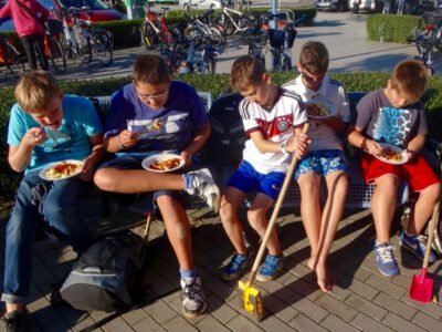 a group of boys sitting on a bench eating food