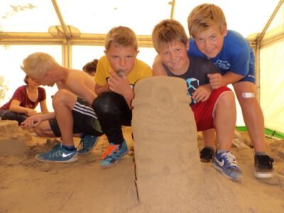 a group of boys posing for a picture with sand sculpture