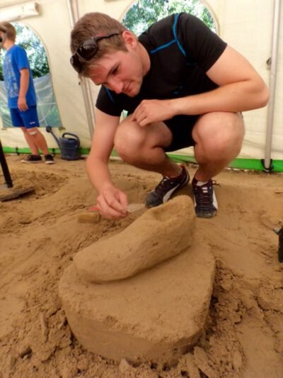 a man in black shirt and shorts kneeling in sand