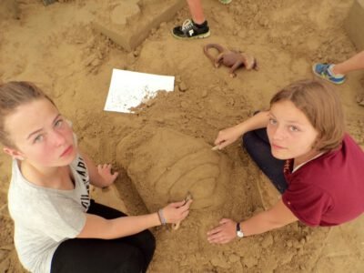 two girls sitting in sand