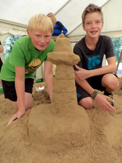 a group of boys posing for a picture with sand sculpture