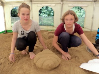 two girls kneeling on sand