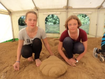 two girls kneeling on sand