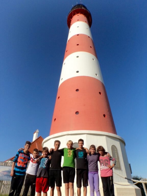 a group of people standing in front of a lighthouse