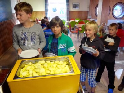 a group of kids holding plates and a container of food