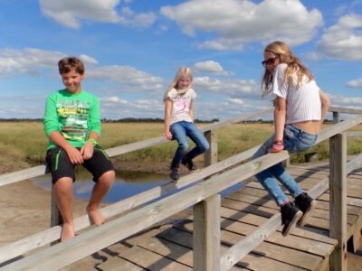 a group of kids sitting on a wooden bridge