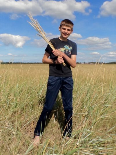 a boy holding a bunch of wheat