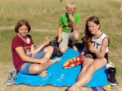 a group of people sitting on a blanket in a grassy field
