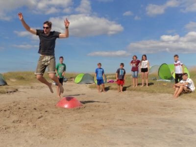 a man jumping over a red object with people in the background