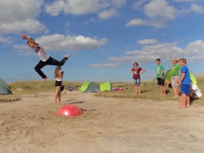 a boy jumping over a red ball