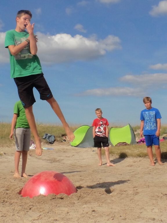 a boy jumping over a red ball