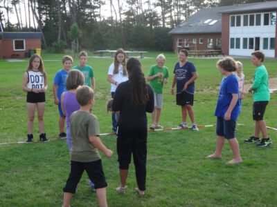 a group of kids standing in a circle in a grassy area