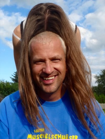 a man with long hair and a woman standing on his head