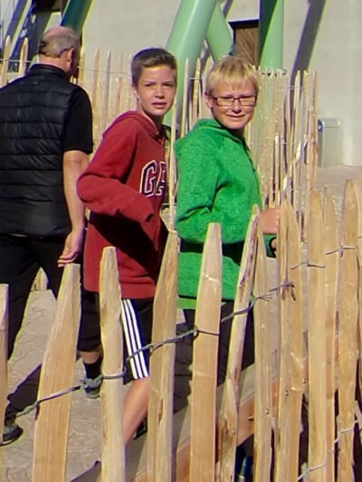 a group of boys standing next to a fence