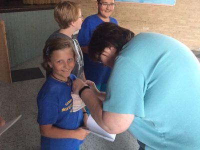 a woman putting a piece of paper on a girl's neck
