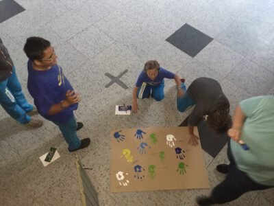 a group of people around a large piece of paper with handprints
