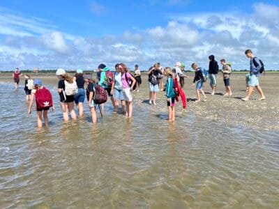 Kinder spielen am Strand im Wasser.