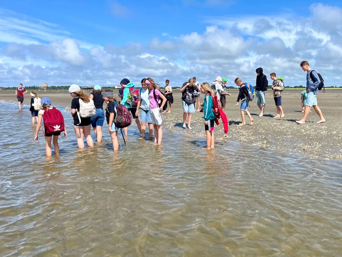 Kinder spielen am Strand im Wasser.
