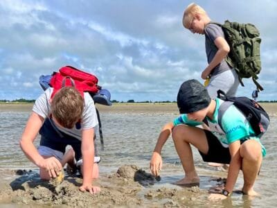 Kinder spielen am Wasser mit Sand.
