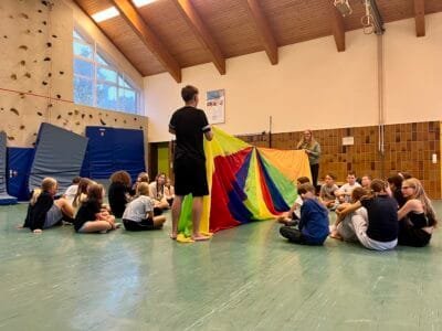 Kinder spielen mit einem Farbtuch.