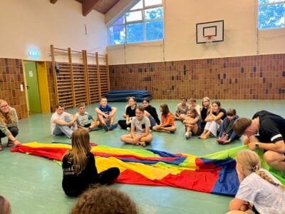 Kinder spielen mit einem Farbentuch.