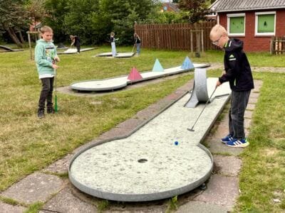 Kinder spielen Minigolf im Freien.