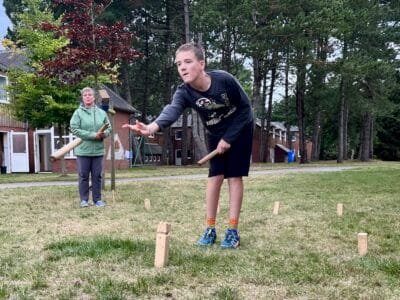 Junge spielt im Freien mit Holzstöcken.