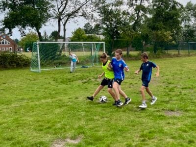 Kinder spielen Fußball im Park.