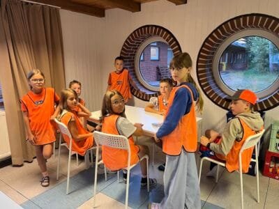 Kinder in orangefarbener Kleidung sitzen.