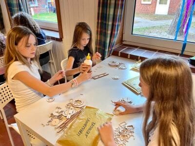Kinder basteln mit Materialien am Tisch.