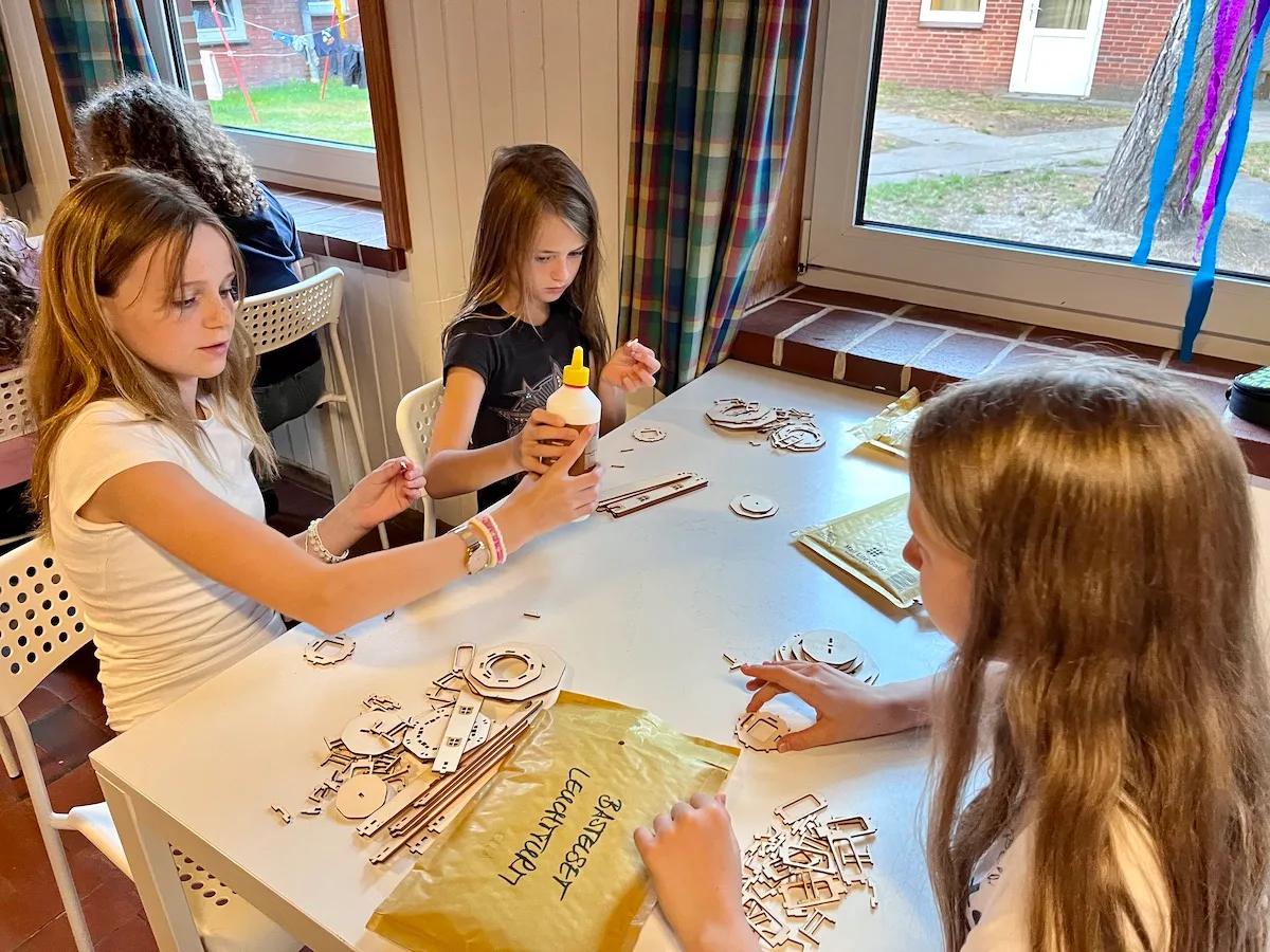 Kinder basteln mit Materialien am Tisch.