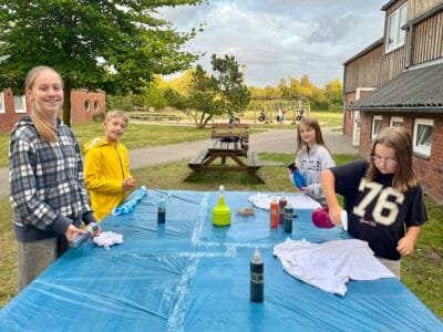 Kinder färben T-Shirts im Freien.
