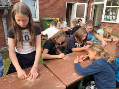 Kinder arbeiten an Bastelprojekten draußen.