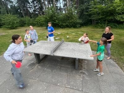 Kinder spielen Tischtennis im Freien.