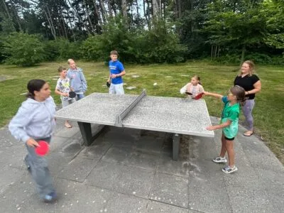 Kinder spielen Tischtennis im Freien.