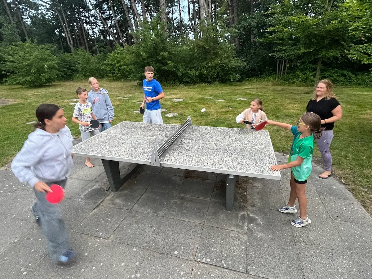 Kinder spielen Tischtennis im Freien.