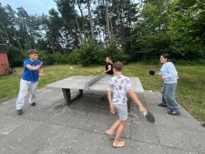 Kinder spielen Tischtennis im Freien.