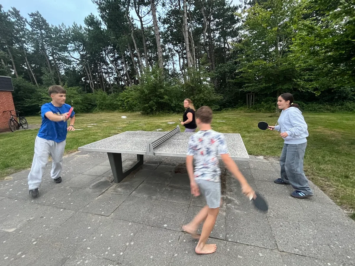Kinder spielen Tischtennis im Freien.
