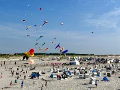 Bunte Drachen fliegen über den Strand.