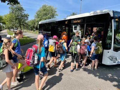 Kinder steigen in den Bus ein.