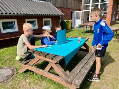 Kinder spielen draußen am Tisch.