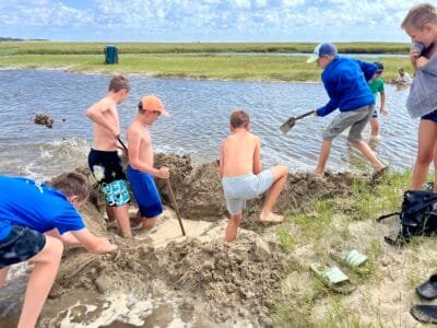 Kinder bauen Sandburg am Wasser